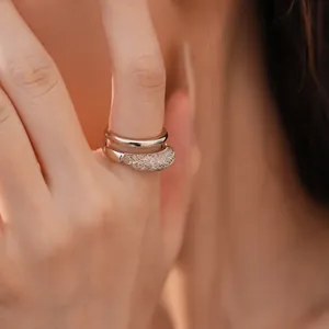 Primer plano detallado de un anillo abierto de doble capa con diseño de malla brillante.
