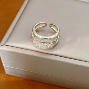 Primer plano detallado de un anillo abierto de doble capa con malla de circón brillante