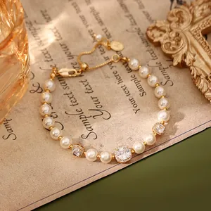 Gros plan d'un bracelet doré avec des perles blanches et des breloques en zircone.