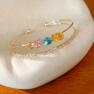 Detaillierte Nahaufnahme eines 18k vergoldeten Doppel-Armreifs mit bunten Zirkonia