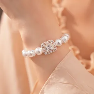 Nahaufnahme eines eleganten Perlenarmbands mit quadratischem Zirkon an einem Frauenhandgelenk