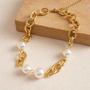 Detailopname van een vintage goudkleurige chunky ketting met grote witte parels.