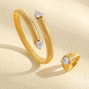 Makroansicht von 18K vergoldetem Streifenarmband und Ring mit herzförmigen Zirkonia-Steinen.