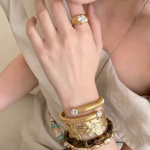 Detailaufnahme von Goldring mit Herz-Zirkonia und Spiralarmband mit Herz-Details