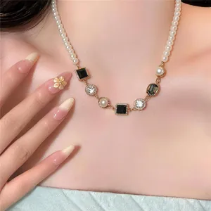 Elegante Franse parelketting met zwarte edelstenen op de hals van een model.