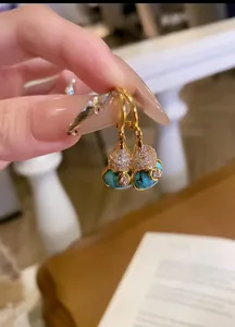 Detailed view of 18k gold plated turquoise and zircon Wu Lou gourd drop earrings