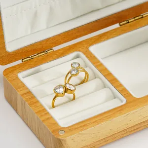 Detalle de dos anillos de acero dorados con piedras de circonita corazón y redondas.