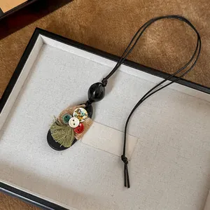 Gedetailleerd overzicht van een etnische houten ketting met knopen en groene kwast