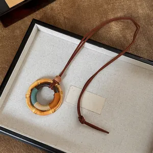 Detail van een handgemaakte houten cirkel hanger ketting met kleurrijke draadwikkels