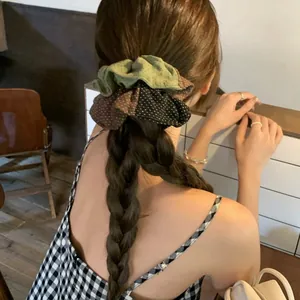 Vue détaillée d'un chouchou à pois en patchwork sur une queue de cheval tressée