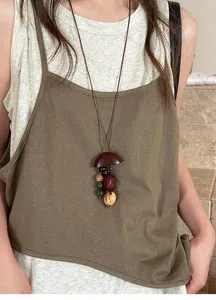 Detailopname van een handgemaakte artistieke houten ketting met notendop hanger en kralen