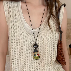 Detailweergave van de houten hanger ketting met groene kwast op een model getoond