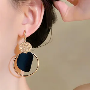 Primer plano de elegantes pendientes colgantes irregulares en oro y negro.