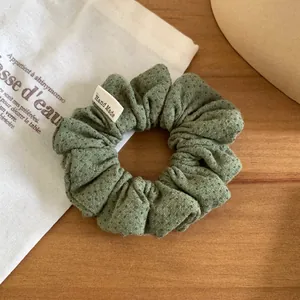 Vue détaillée d'un chouchou en tissu à pois verts doté d'une étiquette Hand Made