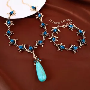 Detail van vintage sieradenset: gouden ketting en armband met blauwe stras en turquoise druppel