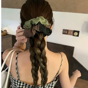 Gros plan d'un chouchou en tissu à pois dégradé et plissé sur une coiffure tressée