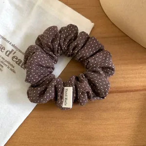 Gros plan d'un chouchou en tissu marron à pois blancs avec étiquette Hand Made