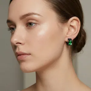 Elegante zwarte creolen van roestvrij staal met smaragdgroen glas getoond op een model