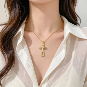 Dettaglio di un'elegante collana con pendente a croce traforata dorata su modella