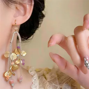 Pendientes étnicos con borlas florales, pétalos dorados y cuentas de colores en una modelo