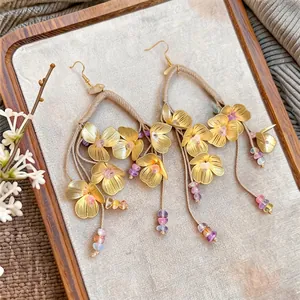 Pendientes de flores doradas étnicas con cuentas de colores y aros tejidos