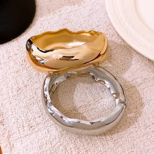 Vue détaillée de bracelets ovales ondulés à la mode avec texture or et argent polie