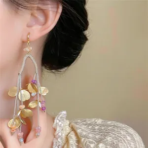 Detalle de pendientes étnicos con borlas, pétalos dorados y cuentas de colores vivos