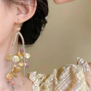 Pendientes elegantes de borlas de hojas doradas con cuentas de colores en el detalle de la oreja
