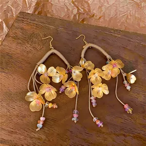 Primer plano de pendientes étnicos de flores con malla dorada y cuentas de colores