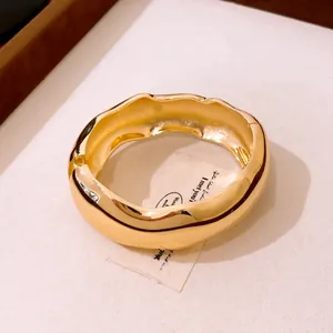 Gros plan d'un jonc doré ondulé minimaliste avec une finition polie et brillante