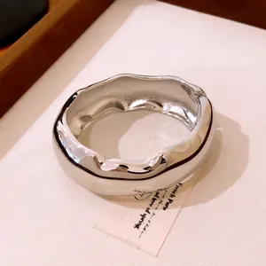 Détail d'un bracelet jonc épais argenté poli avec un design organique ondulé pour femme.