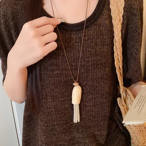 Détail d'un pendentif en bois avec glands de perles sur un collier en cordon cuir