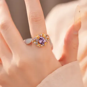 Nahaufnahme eines eleganten vergoldeten Rings mit ovalem violettem Zirkon am Finger
