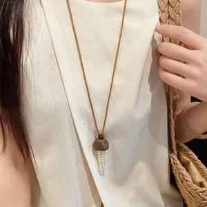 Gros plan détaillé d'un collier avec pendentif en coque de bois et glands de perles