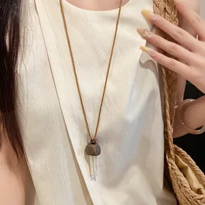 Vue détaillée d'un pendentif en écorce de bois avec franges de perles sur cordon.