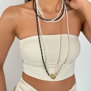 Détail du collier rétro multicouches en perles et acrylique avec grande boule dorée.