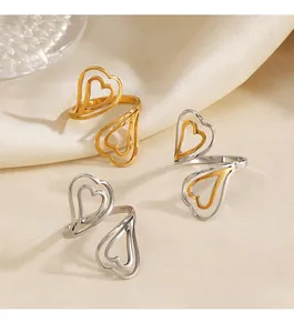 Vue rapprochée de trois bagues en acier titane avec motifs de double cœur évidé.
