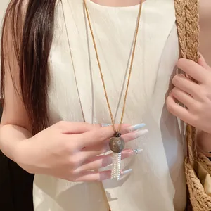 Vue détaillée du pendentif en bois et perles sur une longue chaîne dorée élégante