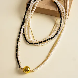 Détail montrant les couches de perles et perles noires avec un pendentif boule dorée