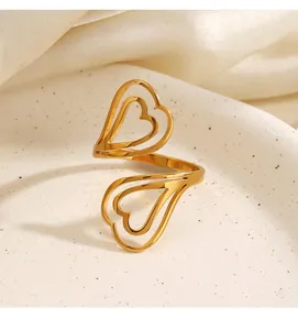 Vue détaillée d'une bague ouverte double cœur en acier titane doré sur un plat décoratif.