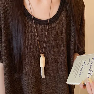 Vue détaillée du collier en cordon de cuir avec pendentif en bois et glands en perles