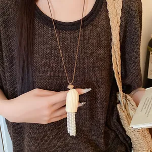 Collier artisanal en bois avec glands en perles blanches sur un cordon en cuir marron