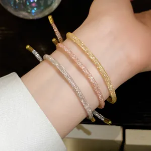 Close-up van drie glinsterende zirkoon mesh armbanden in zilver, goud en roségoud