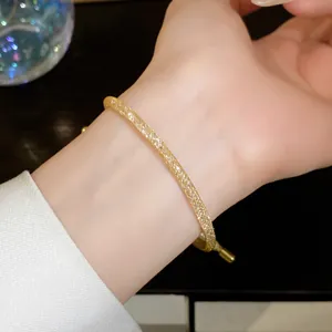 Close-up van gouden mesh zirkoon trekarmband om de pols, elegant en minimalistisch sieraad