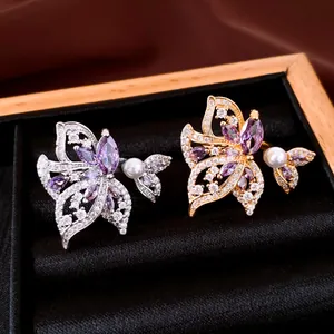 Vista detallada de elegantes anillos de alas bañados en oro 18k con circonitas y perlas