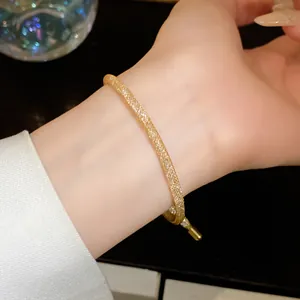 Detailopname van elegante gouden mesh trekarmband met fijne zirkonia details om de pols.