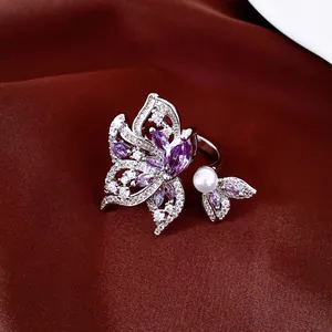 Detalle macro de anillo chapado en oro de 18k con alas de mariposa de circón púrpura y perla