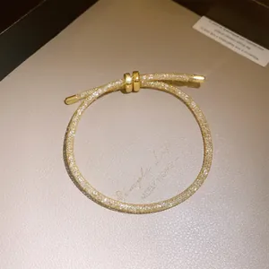 Detailopname van een sprankelende gouden zirkoon schuifarmband met mesh textuur