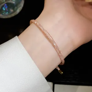 Detailopname van een glinsterende roségouden zirkoonarmband om de pols van een elegante vrouw