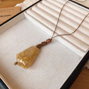 Detalle del collar con colgante de resina con escamas de oro y cuentas de madera
